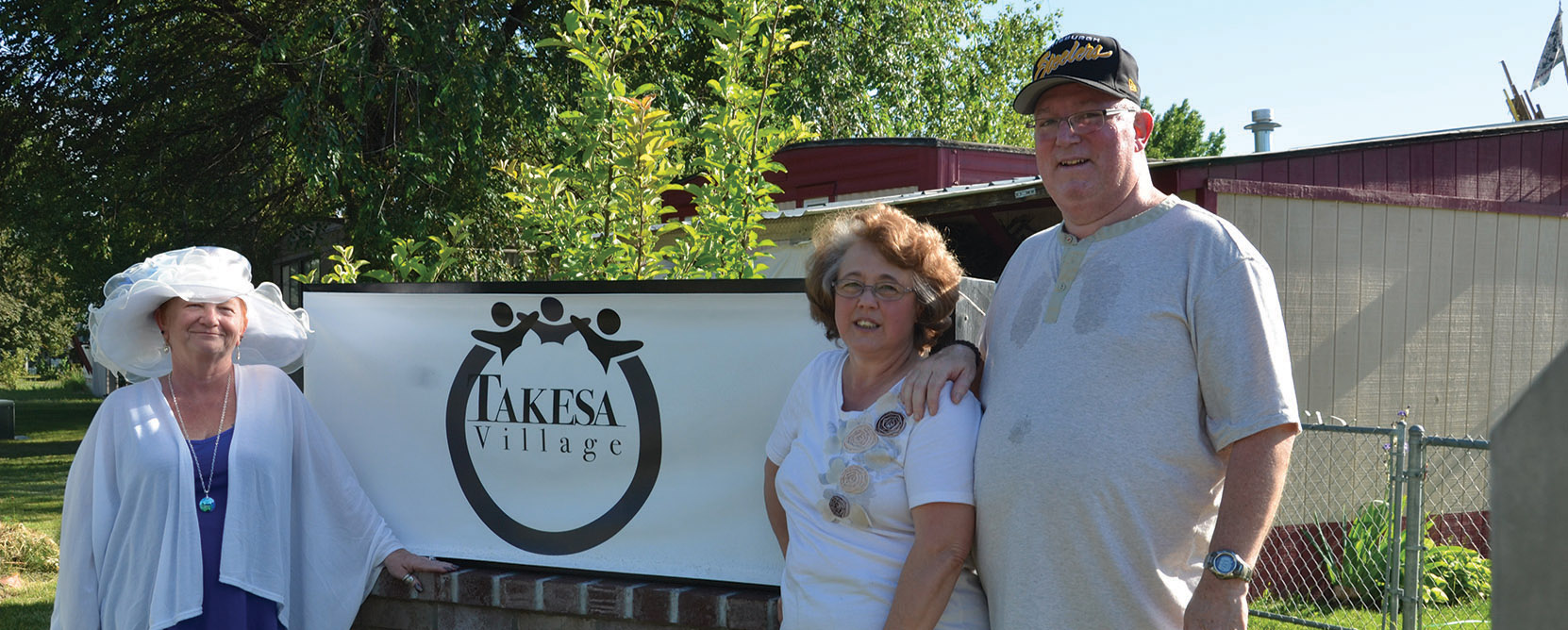 Residents pose in front of Takesa Village sign.